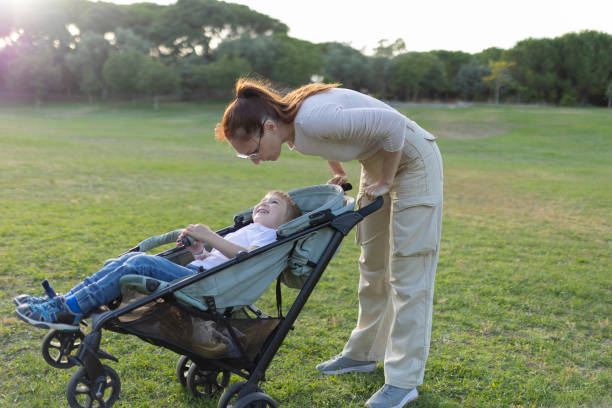 istock Mother talking with her son sitting in a stroller in a park 2197830164