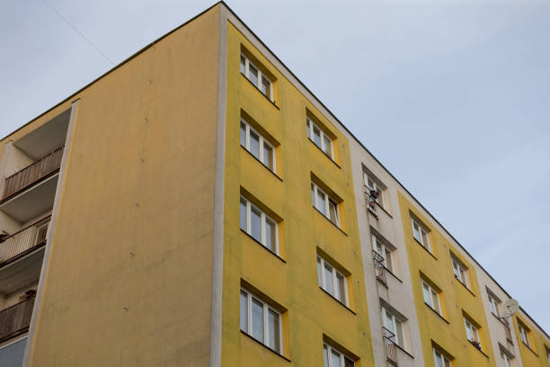 A bright yellow apartment building stands prominently against a clear blue sky in the background, creating a vibrant urban scene