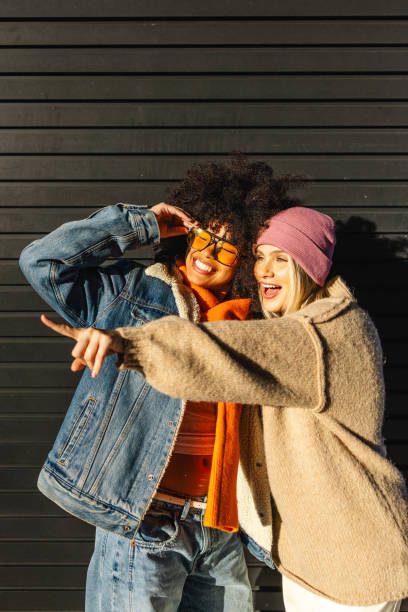 istock Two multiethnic female friends are hugging and pointing while enjoying a sunny day together outdoors 2197839052