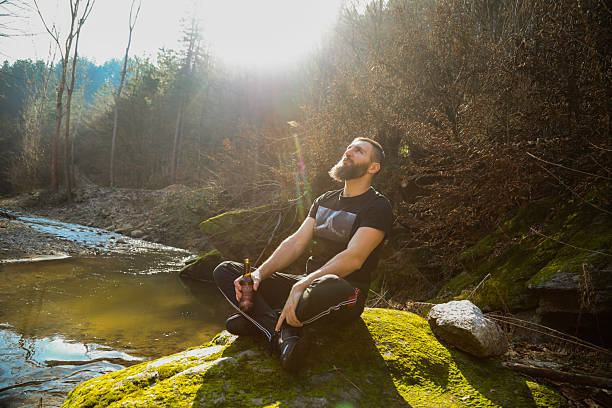 istock He drinks his beer and smokes a cigarette in nature by the river. 2197839180