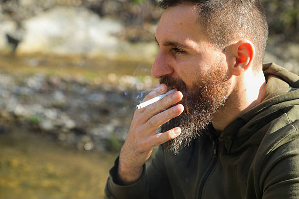 istock He drinks his beer and smokes a cigarette in nature by the river. 2197839305