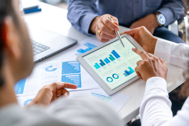 istock Close up of three people looking at financial data with graphs and charts. 2197844261