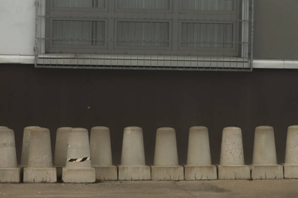 Concrete barriers are positioned in alignment next to a wall featuring a window, effectively highlighting an urban environment scenario