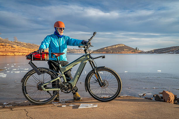 istock Senior cyclist with a touring e-bike with action camera mounted on handlebar at shore of frozen Horsetooth Reservoir in Colorado foothills. 2197853018