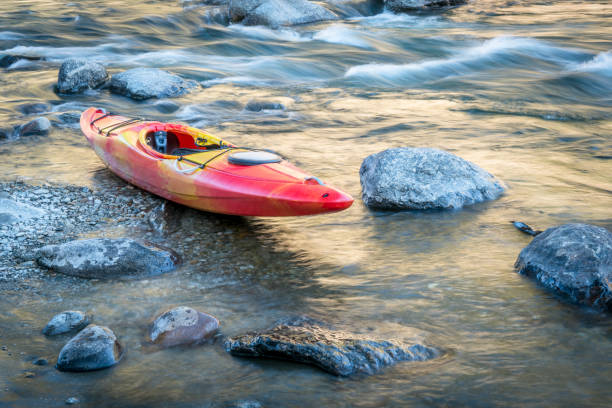 whitewater kayak on a river shore with a rapid in background