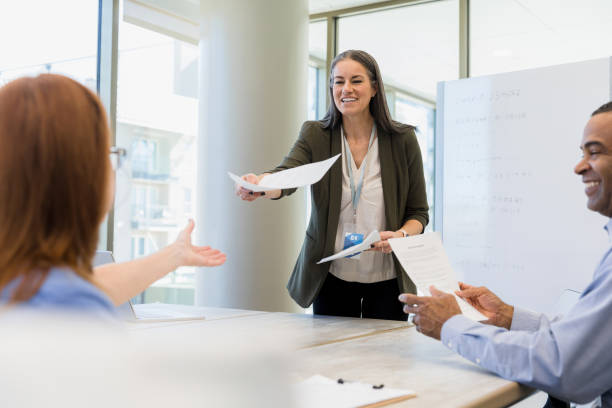 istock Businesswoman Distributing Documents in a Meeting 2197853590