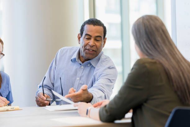 istock Mature Man Explains Documents to Female Colleague in Office 2197853596