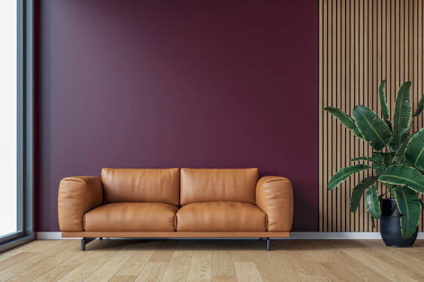 istock A modern minimalist interior with a brown leather sofa, a potted plant in front of an empty burgundy plaster, partly hardwood paneled wall background with copy space, a large window by one side 2197855561