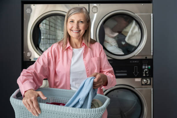 istock Mature woman using self-service washing machine in laundromat 2197861187