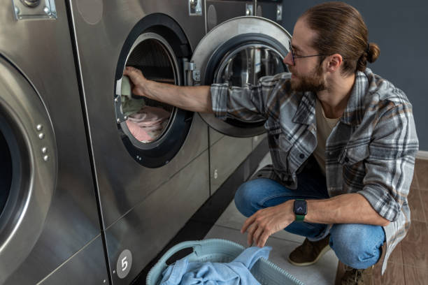 istock Positive man in self service commercial laundry using washing and drying machine 2197861306