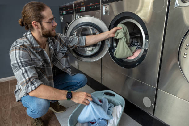 istock Man using modern technology in public laundry store washing clothes in automatic washing machine 2197861308