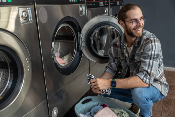 istock Positive man in self service commercial laundry using washing and drying machine 2197861316