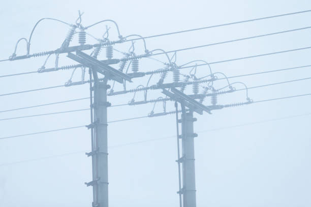 Power lines stretch across the landscape in foggy conditions, highlighting outdoor infrastructure against a moody and atmospheric environment