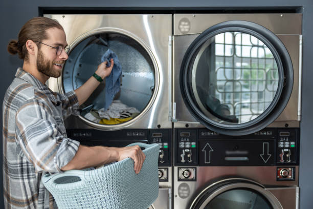 istock Man in laundromat using commercial washing machine while completing his laundry chores 2197861422