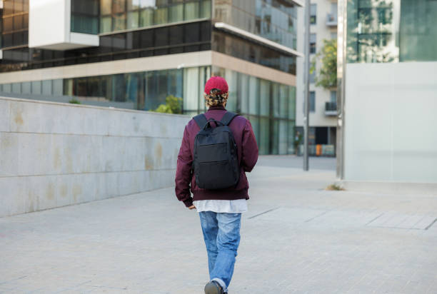 istock Businessman walking away backpack and red cap 2197865258