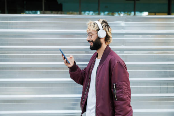istock Stylish man enjoying music and browsing smartphone in urban setting 2197866195