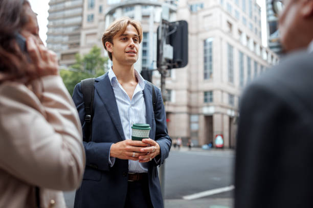 istock Young well dressed businessman talking with his colleagues while having coffee break outdoors in a city 2197869538