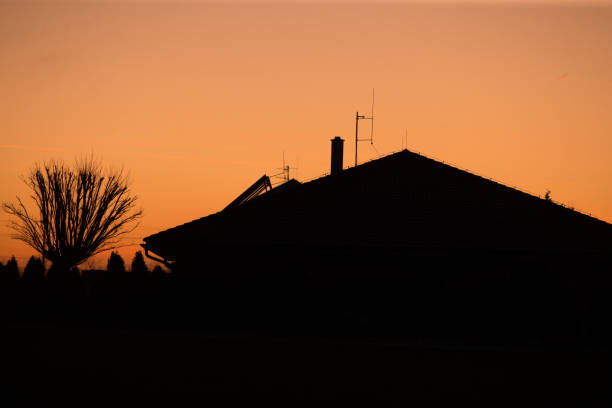 Silhouette of a Building Against an Orange Sunset Sky. Silhouette of a building stands out against the vivid orange hues of a sunset sky. The dramatic contrast captures the beauty evening.