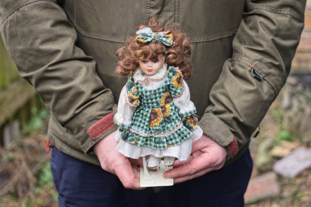 hands hold one plastic doll toy brown-haired on autumn street