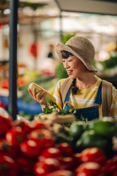 istock Asian female market customer holding celery and corn choosing fresh vegetables 2197876501