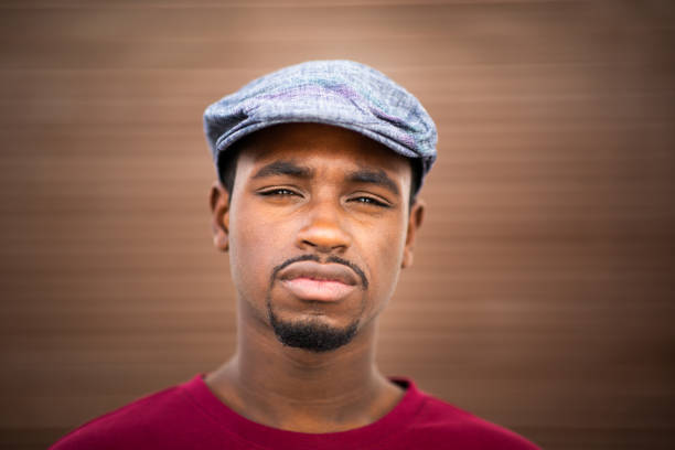 Close up portrait of handsome young african american man with cap on brown background