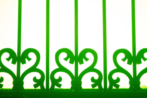 Crafted wrought iron gate featuring intricate decorative patterns is silhouetted against light background