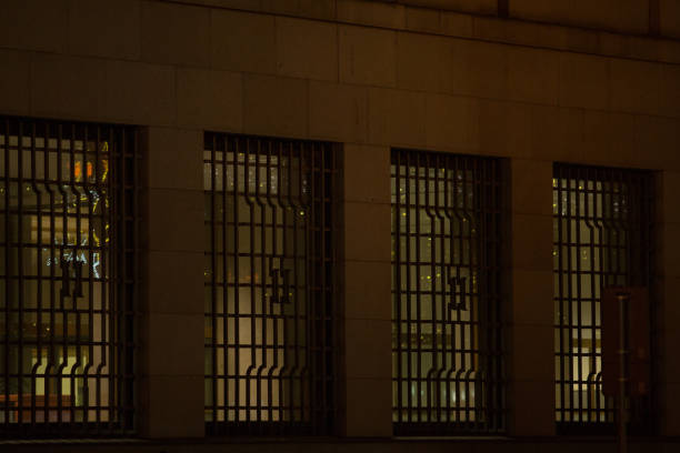 Grated windows on a striking building facade are beautifully illuminated, creating a captivating view at night under the city lights