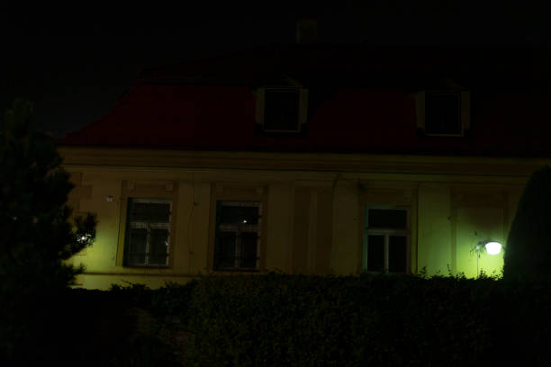 A charming house featuring a bright red roof is beautifully illuminated at night, creating a picturesque scene against the darkness