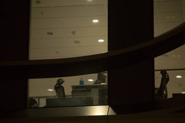 Office Building with Large Windows Viewed from Outside at Night. An office space with large, illuminated windows is captured from an exterior perspective during the evening or night.