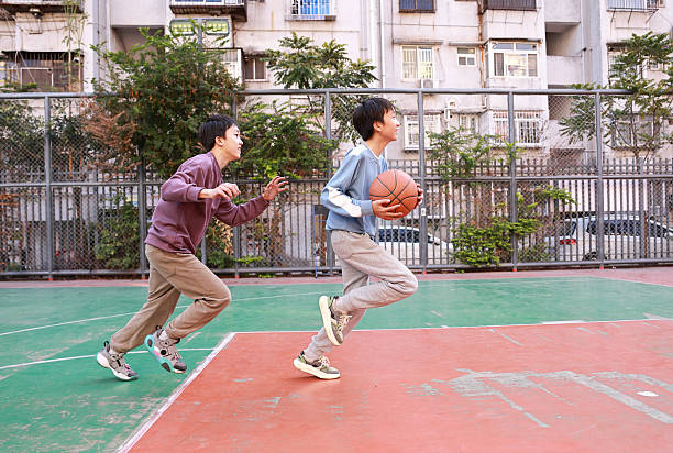 Two young boys playing basketball in a park