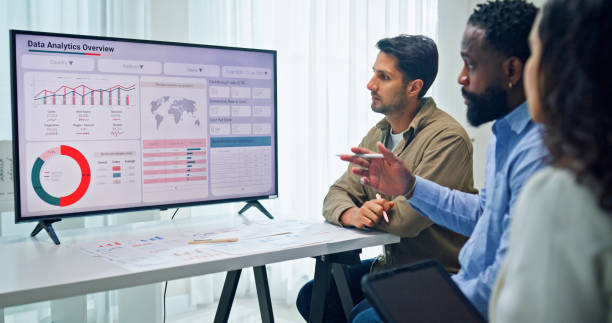 istock Group of business professionals meeting reviewing global data analytics presented on a large screen, discussing strategy and growth at the office. Finance meeting concept. 2197902465
