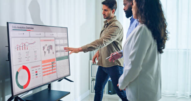 istock Group of business professionals meeting reviewing global data analytics discussing data analytics during a presentation, discussing strategy and growth standing at the office. Finance meeting concept. 2197902480