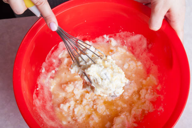 Making cupcakes at home. A woman prepares Easter cakes in the kitchen, beating the dough with a whisk