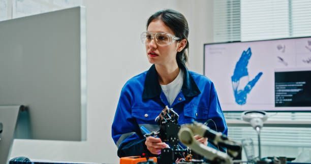 istock Young female engineer using multimeter and soldering tools to test and repair robotic arm in tech lab. AI and Robotics Development. 2197913294