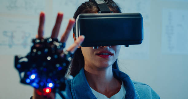 istock Closeup Young female engineer working late using virtual reality and gloves gestures to interact with digital simulation in tech lab at night. Machine learning, AI and Robotics Development. 2197913333