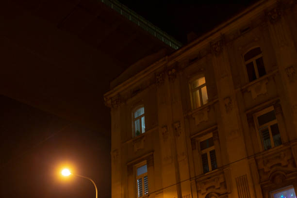 A tall building stands majestically with a bright street light illuminating the area in front of it during the dark hours of night