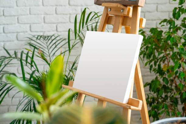 istock Artist's easel set up with a blank canvas surrounded by indoor plants in a cozy studio environment 2197918013