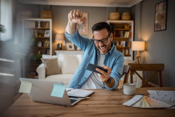 istock Businessman playing mobile phone games in home office 2197920047