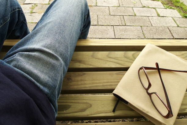 A book, glasses, jeans on a bench