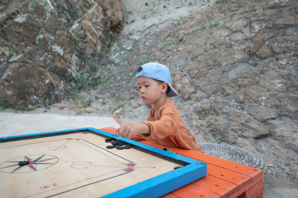 istock Child Playing Carrom Game with Intense Focus Outdoors 2197920633