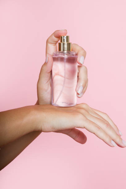 istock Woman spraying perfume on her wrist on pink background 2197925472