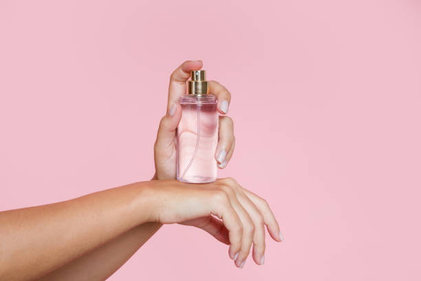 istock Woman spraying perfume on her wrist on a pink background 2197925495