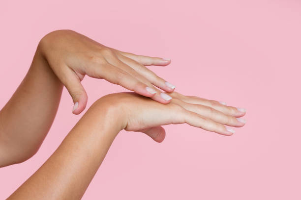 istock Woman applying moisturizing cream on her hands on pink background 2197925545