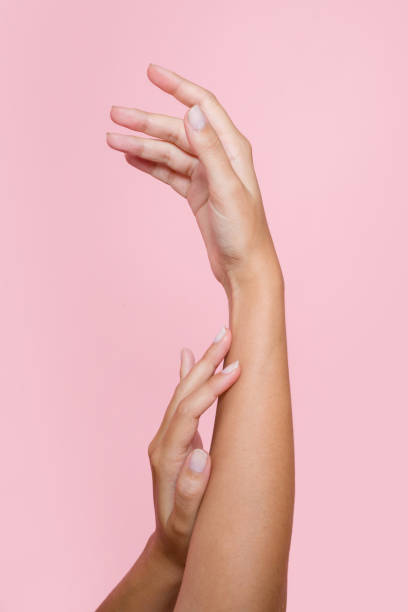 istock Woman gently touching her arm with her hand on a pink background 2197925636
