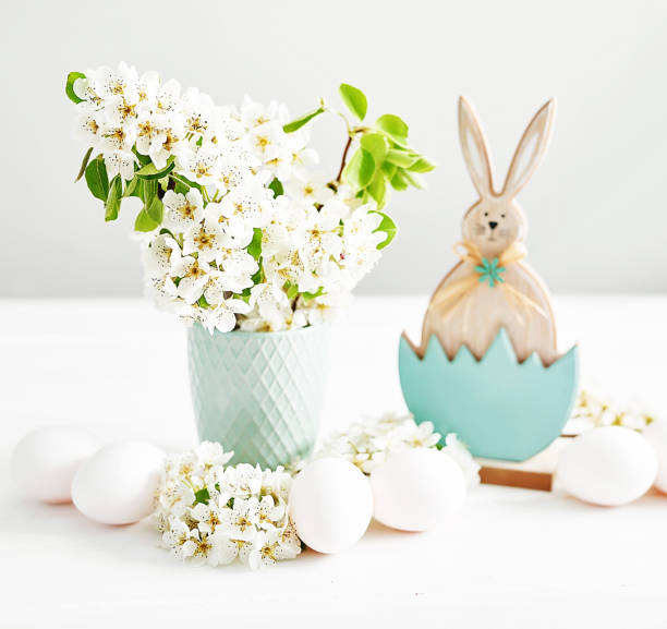 Easter bunny and White Easter eggs and spring branch with flowers on wooden background. Spring easter greeting card.Flowers Cherry flowering.Spring flowers. Beautiful Orchard.Springtime.