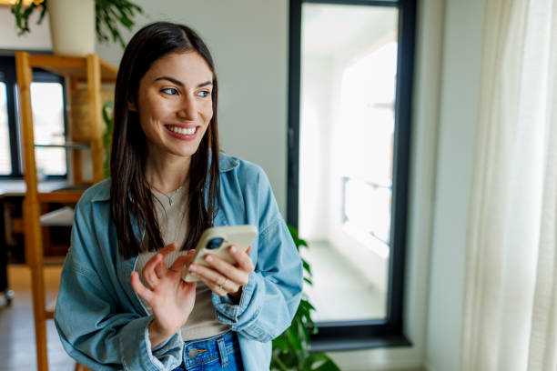 istock Young Adult Woman Smiling While Using Smartphone 2197927740
