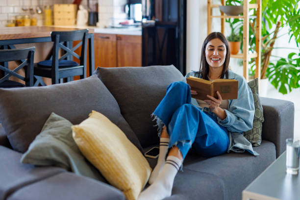 istock Young Woman Relaxing and Reading on Couch 2197927881