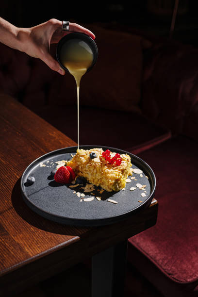 istock Delicious dessert on a plate with fruit and syrup being poured in a cozy cafe setting 2197928337