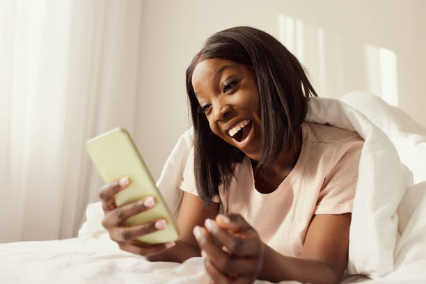 istock Cheerful black woman using smart phone during morning in a bed. 2197928370