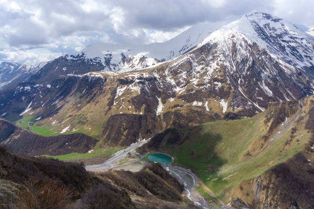 istock View from above on a small emerald lake between high mountains covered with snow. Tributaries of the river are visible. Mountains, hills, cloudy sky in the background 2197929401